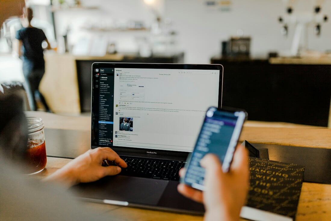 Person asking a question on a phone next to a laptop